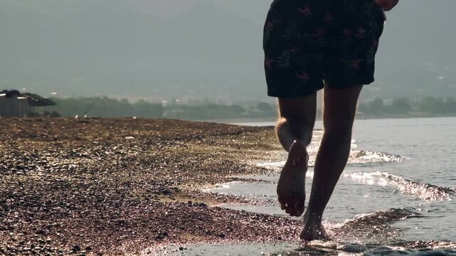 A slow motion video of an eight year old female one eyed pitbull running together with her athletic forty year old male owner on a sunny morning sandy beach.