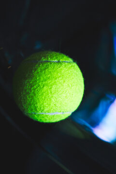 Neon tennis ball on a dark glossy surface.