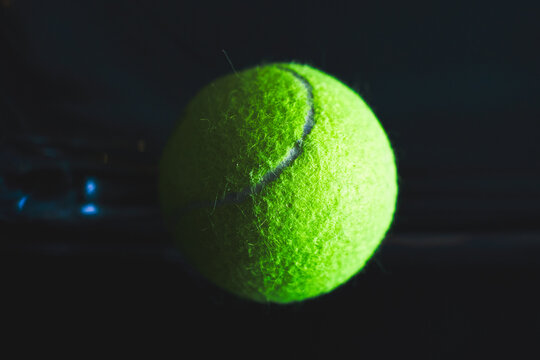 Neon tennis ball on a dark glossy surface.