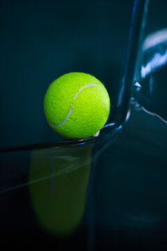 Neon tennis ball on a dark glossy surface.
