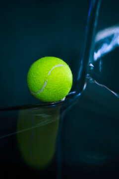 Neon tennis ball on a dark glossy surface.