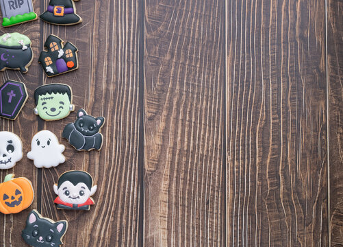 Halloween gingerbreads, pumpkin, cat, ghost, tombstone over wooden background with copy space