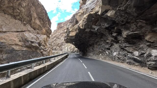 POV video of a vehicle approaching a rock overhang forming a natural tunnel above the road and a deep gorge - Spiti Valley Himachal Pradesh India | Himalayan road trip GoPro dashcam 4K