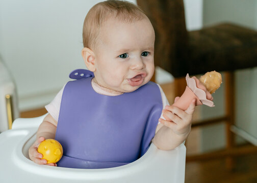 Cute infant chewing fresh fruit from teether feeder