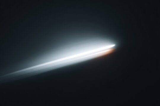 A comet in the dark sky illuminated by a bright light. the comet is in the center of the surrounded by a dark background.