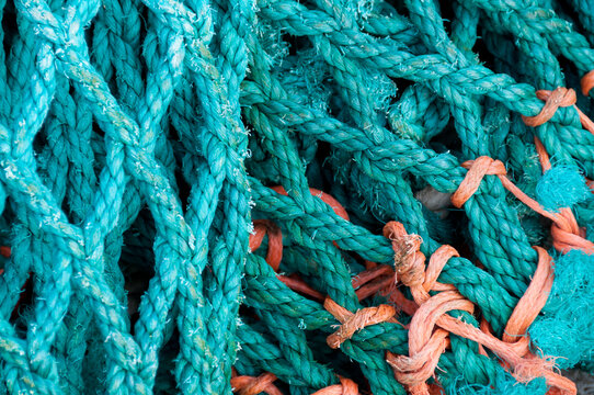 View of a tangled pile of vibrant turquoise and orange fishing nets with textured ropes and knots in Canada.