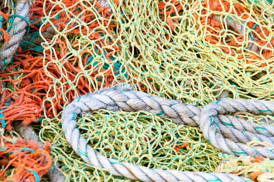 View of colorful orange, yellow, and green fishing nets tangled with a thick braided rope in Canada.