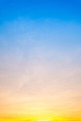 Naklejka premium Sky sunset,Beautiful sunrise sky with vibrant gradient orange and gold colors and soft blue, Clear atmosphere with wispy clouds. Peaceful, perfect for background and copy space, vertical