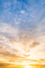 Naklejka premium Sky sunset,Beautiful sunrise sky with vibrant gradient orange and gold colors and soft blue, Clear atmosphere with wispy clouds. Peaceful, perfect for background and copy space, vertical