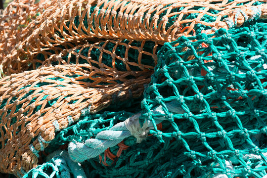 View of tangled orange and green fishing nets with thick ropes piled together in Canada.