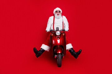 Obraz premium Santa Claus on a red scooter with sunglasses celebrating Christmas in a playful holiday portrait