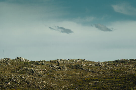 View of the rocky landscape of Las Animas with rugged terrain, scattered stones, and sparse vegetation under a cloudy sky in Tandil, Provincia de Buenos Aires, Argentina.