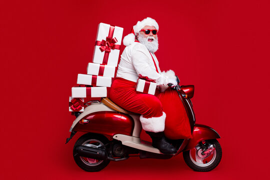 Santa Claus on a red scooter delivering Christmas gifts with sunglasses and a sack on vibrant background