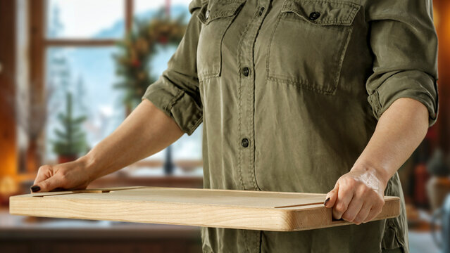 Woman holding wooden tray with copy space &ndash; cozy winter interior concept.