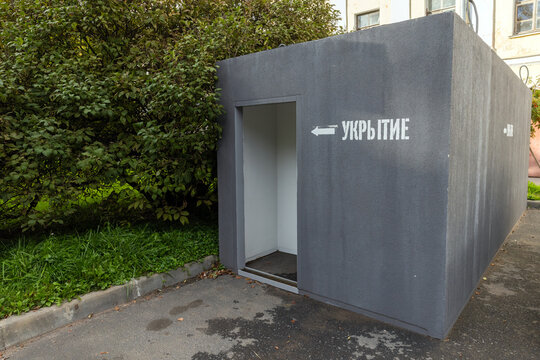 An urban emergency shelter entrance with the Russian word Shelter stenciled on a gray concrete bunker beside greenery, conveying civil defense, safety, preparedness and municipal emergency architectur