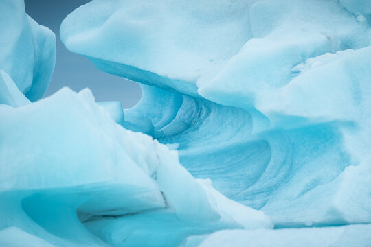 View of Vatnajokull glacier ice formations with intricate blue textures and smooth curves, Iceland.