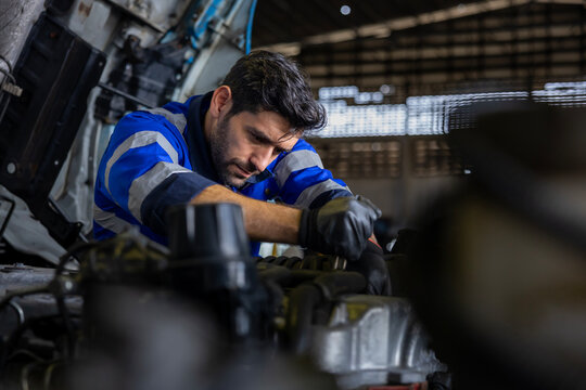 Caucasian mechanic is inspecting the diesel truck engine after annual check up in the professional garage and maintenance all the filter and gear for safety driving concept