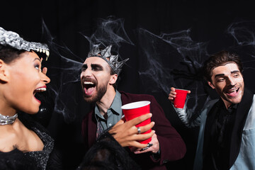 Obraz premium Cheerful multicultural friends celebrating Halloween at a lively costume party