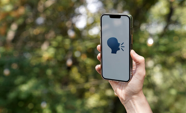 hand holding a smartphone with an icon of a person speaking, concept of communication, discussion, speak up