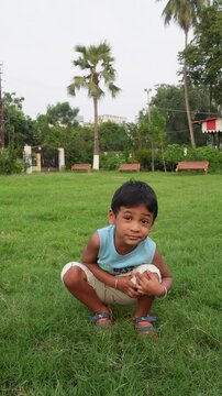 Young child squatting on a green lawn outdoors