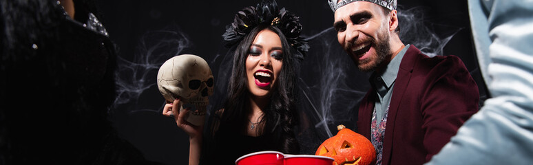 Obraz premium Multicultural friends enjoy a vibrant Halloween party with spooky costumes, banner 