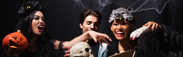 Obraz premium Multicultural friends enjoy a lively Halloween party dressed in fun costumes together, banner 