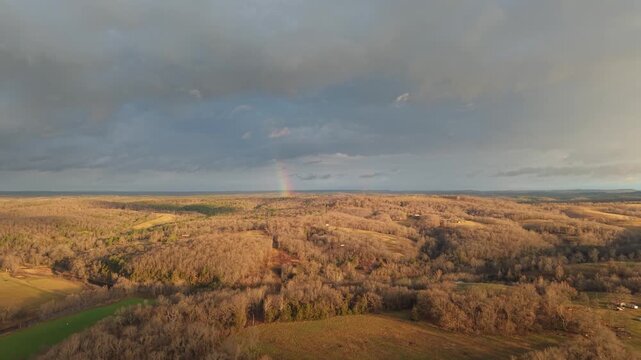 Aerial double rainbow and storm clouds over rolling hills, Ozarks