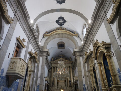 View of the ornate interior of Capela de Santa Catarina church featuring vaulted ceilings, golden altars, blue and white azulejo tiles, and a large crystal chandelier in Porto, Portugal.