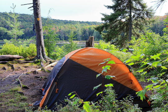 Backpacker sets up camp at a primitive campsite next to a remote pond in the Adirondack wilderness