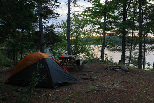 Backpacker sets up camp on primitive lakeshore campsite within the Adirondack wilderness