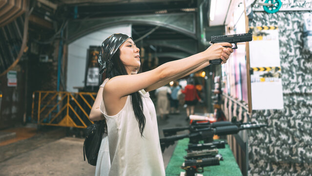 Two young asian women enjoy playing bb gun game at shooting booth