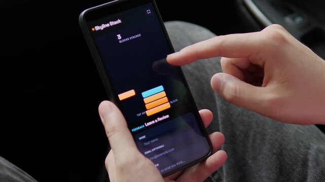 A person plays a fast-paced block stacking game on a smartphone, capturing casual mobile gaming, hand-eye coordination, instant entertainment and interactive digital leisure.
