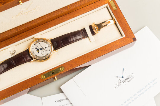 Luxury Breguet Classique wristwatch featuring a rose gold case, silver guilloch&eacute; dial, moonphase indicator, power reserve, and leather strap.