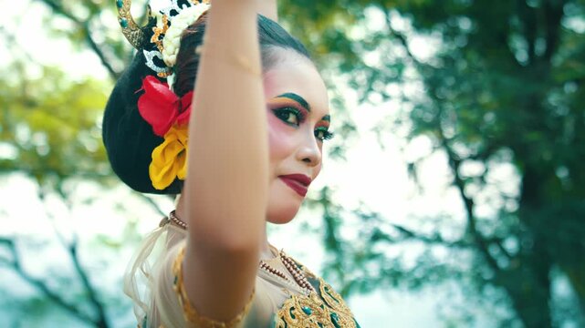 Medium shot capturing the elegance of a Javanese dancer as she moves her hands fluidly around her head and golden crown.