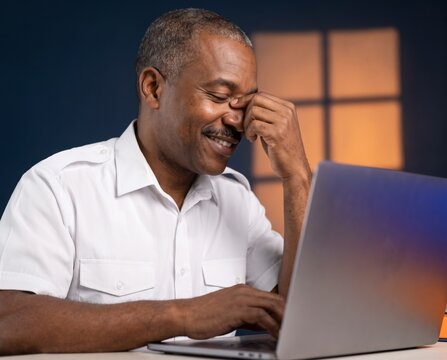 Relaxed mature man laughing  while remote working typing on laptop at desk
