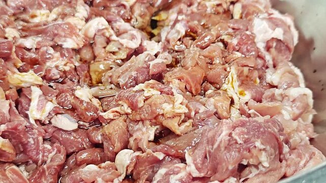 Pouring dark soy sauce or marinade onto fresh sliced raw meat.