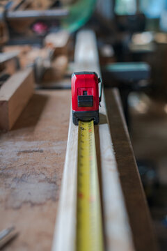 View of a red tape measure extended along a piece of timber in a workshop in Looe, Cornwall, United Kingdom.