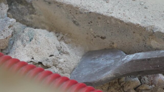 Industrial hammer chisel aggressively breaking up thick concrete foundation during site renovation. Macro shot.