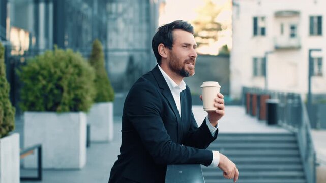 Focused Caucasian Male Businessman Enjoying Coffee While Standing In Urban Setting, Taking A Break At Modern Office Space, Presenting Business Concept.