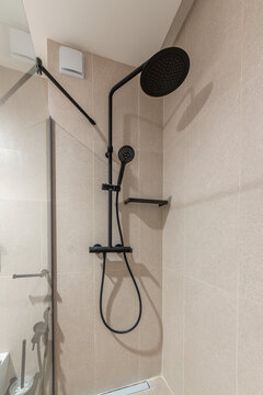 Stylish modern shower with black matte fixtures, a rainfall shower head, and gray tile. Elegant bathroom interior design for a contemporary home or hotel.