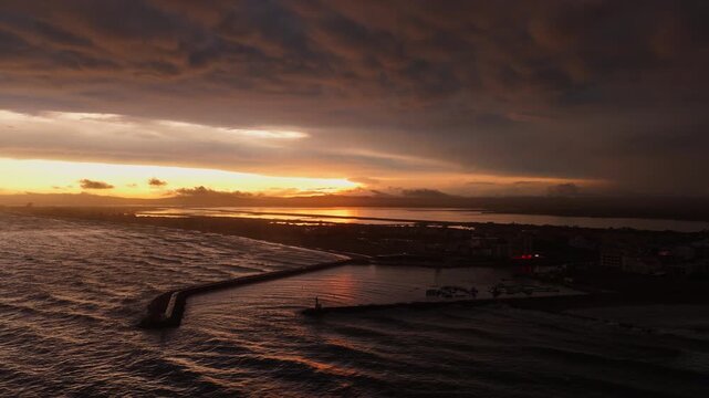 Aerial sunset over Carnon harbor breakwater lagoon and stormy sea