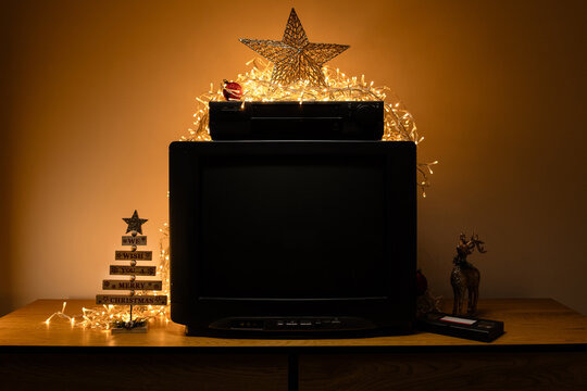 Vintage CRT TV with VCR, fairy lights and Christmas decor, featuring a blank dark screen for mockup use, retro media themes and holiday nostalgia