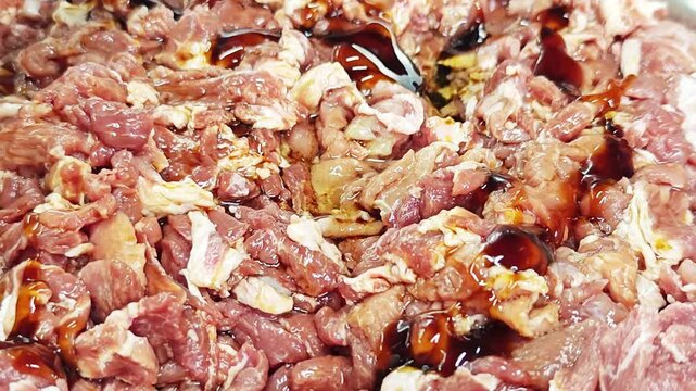 Pouring thick dark oyster sauce or marinade onto fresh sliced raw meat.