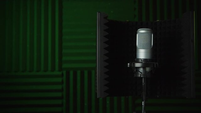 Professional condenser microphone mounted inside an acoustic isolation shield in a dark recording studio