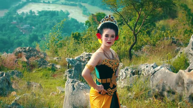 A majestic shot of a woman in traditional royal attire standing confidently on a hill, with a breathtaking view of green valleys.
