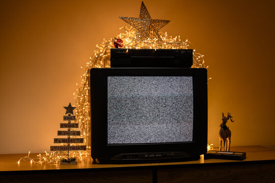 Retro CRT television with VCR and Christmas lights, static noise screen in festive holiday interior