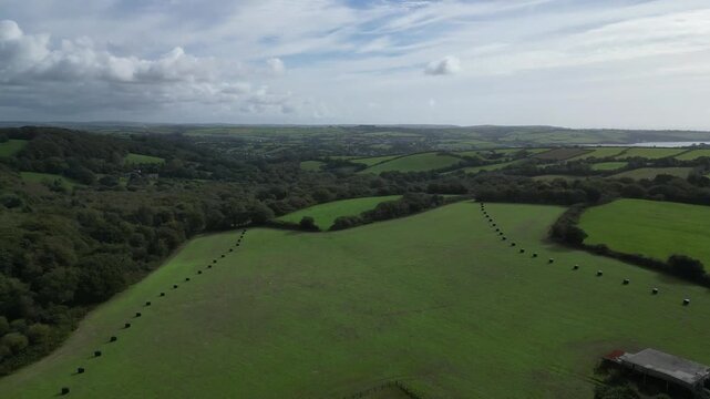St Blazey, Cornwall, England: DRONE VIEWS: Flying east from the Eden Project over wrapped hay bales; the sea at Par Sands can be seen (top right). Cornwall is a popular UK holiday destination.