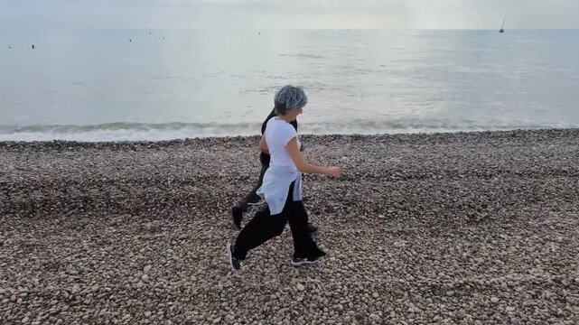 Pareja madura echando una carrera por la playa en oto&ntilde;o