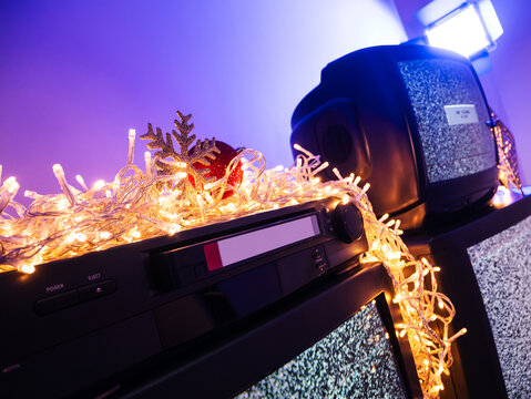 Vintage VHS player with videocassette surrounded by Christmas lights and holiday decorations, retro home video technology concept