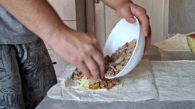 Making a simple wrap with meat, vegetables, and spices in a kitchen